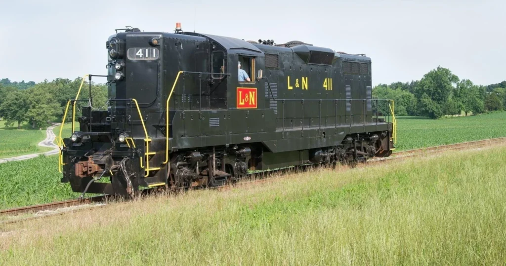 A black L&N diesel locomotive numbered 411 travels on tracks through a green, grassy landscape.