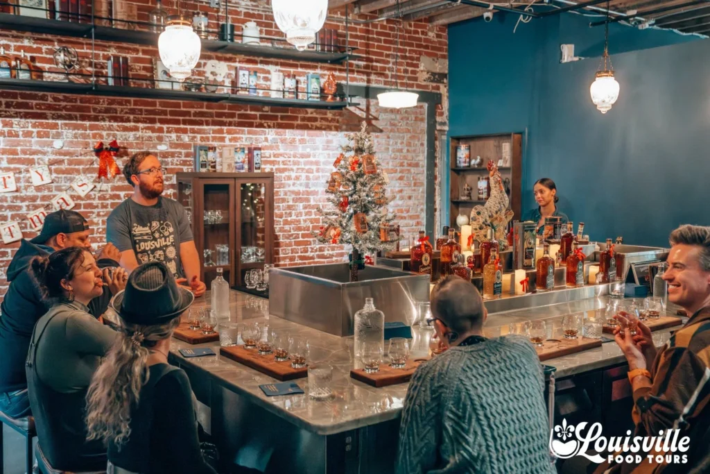 A group of people sit around a bar in a rustic room with exposed brick walls, pendant lights, and a Christmas tree.
