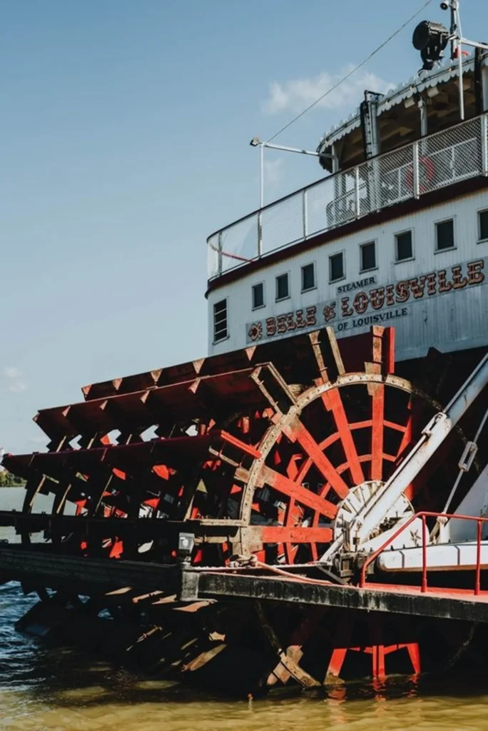 The large red paddlewheel of the Belle of Louisville steamboat on a river.